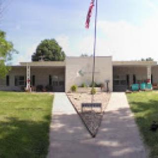 A view of the school building with a flag and pathway leading to the entrance.