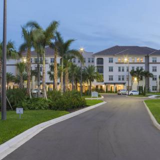 A residential apartment complex surrounded by palm trees in the evening light.