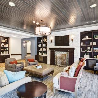 A modern and cozy living room with elegant furniture, a fireplace, and built-in bookshelves.