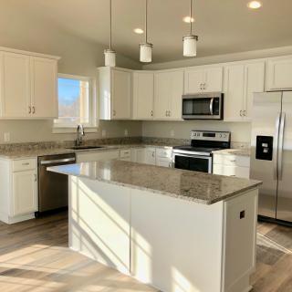A modern kitchen with white cabinets and stainless steel appliances.