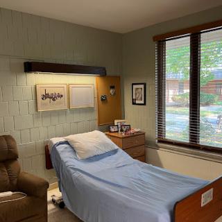 A cozy hospital room featuring a patient bed, recliner, and natural light from the window.
