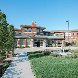 A modern residential building with landscaped surroundings on a sunny day.