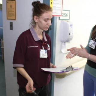 A nurse holding a clipboard is engaged in discussion with a colleague in a hospital setting.