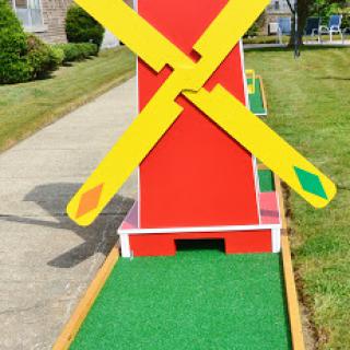 A vibrant windmill structure at a mini golf course, inviting players to enjoy a fun game in a scenic outdoor setting.