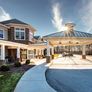 A modern residential building with a covered driveway and sunlight streaming through the sky.