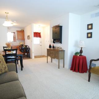 A well-lit living room with a dining area, featuring comfortable furnishings and tasteful decor.