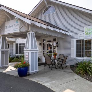 The image shows the entrance of a building with outdoor seating and signage.