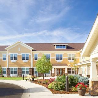 A well-maintained residential building with landscaped gardens under a clear blue sky.