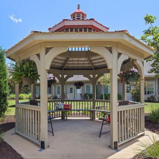 A wooden gazebo in a landscaped garden setting.