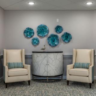 A stylish seating area with two beige chairs and blue wall art.