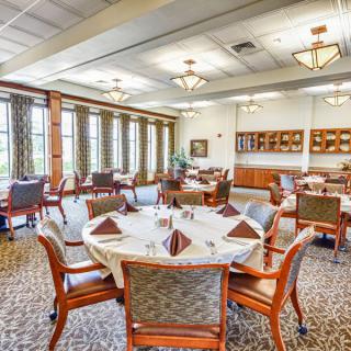 An elegant dining room with neatly arranged tables and chairs, featuring large windows and stylish decor.
