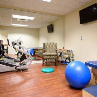 A small gym room equipped with exercise machines and a blue exercise ball.