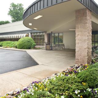 A modern building entrance surrounded by landscaped flowers and greenery.