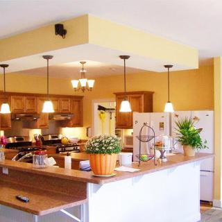 A cozy kitchen featuring wooden cabinets, pendant lighting, and decorative plants.