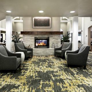 A modern lobby featuring a cozy seating area with a fireplace and armchairs.