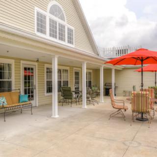 A spacious patio with comfortable seating and bright red umbrellas, attached to a house.