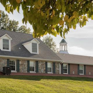 A suburban house with a well-maintained lawn and trees in the foreground.