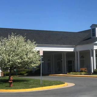 A sunny day view of a building entrance with landscaping.