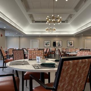 A spacious dining room with neatly arranged tables and chairs, adorned with elegant lighting fixtures.