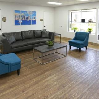 A modern living room with a black sofa, blue chairs, and a wooden floor.
