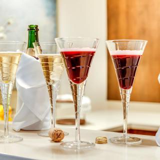 Elegant glasses filled with champagne and a red cocktail, set on a bar for a celebration.
