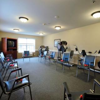 A well-lit exercise room with chairs and stationary bikes arranged in a spacious layout.