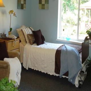 A cozy bedroom with a single bed and a large window allowing natural light in.