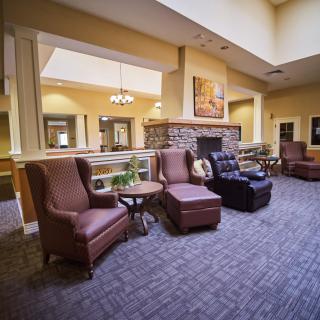 A cozy lounge area featuring comfortable armchairs and a fireplace, accented by warm lighting and carpeting.