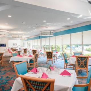 A bright and elegantly set dining area with tables and chairs, featuring large windows that allow natural light to fill the space.