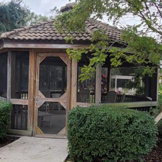A wooden gazebo surrounded by greenery in a garden setting.