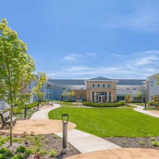A view of a modern building surrounded by landscaped gardens and pathways under a clear blue sky.