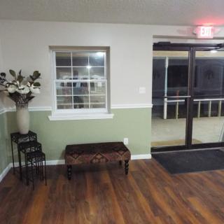 A small lobby area with a bench, window, and decorative flowers.