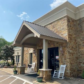 A charming stone building entrance with rocking chairs, inviting visitors to relax.