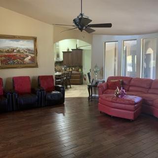 A spacious living room with red sofas, wood flooring, and a ceiling fan.