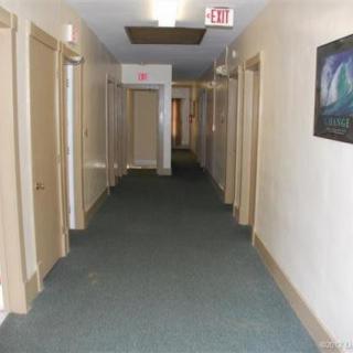 A long, carpeted hallway with multiple doors on both sides.