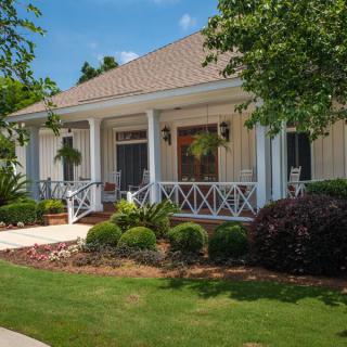 A charming house with a front porch and well-maintained garden on a sunny day.