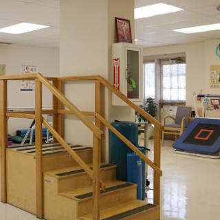 A view of a therapy room featuring stairs and various rehabilitation equipment.