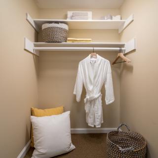 A well-organized closet with a robe hanging and baskets on shelves.