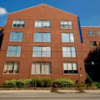A multi-story brick building with large windows, situated in an urban environment.