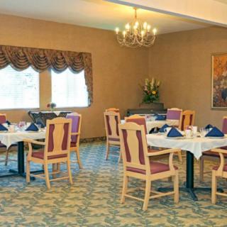 An elegant dining room with neatly arranged tables and chairs, featuring a chandelier and decorative curtains.