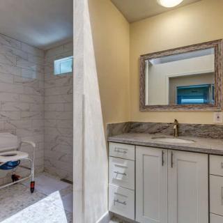 A modern bathroom featuring an accessible shower and a vanity with a large mirror.
