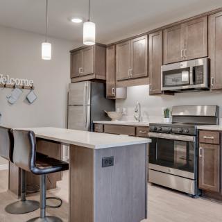 Modern kitchen with a central island, stainless steel appliances, and pendant lighting.