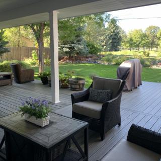A cozy patio overlooking a lush garden, featuring comfortable outdoor furniture and potted plants.
