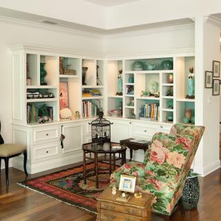 A cozy living room corner with built-in white bookshelves, a floral armchair, and decorative accents.