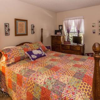 A cozy and colorful bedroom featuring a quilted bedspread and warm decor.