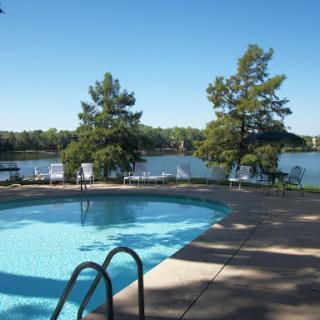 A serene outdoor swimming pool overlooking a tranquil lake on a beautiful sunny day.