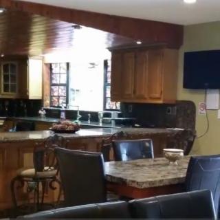 A modern kitchen and dining area with wooden cabinets and marble countertops.