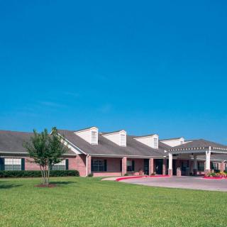 A residential building with a well-maintained lawn under a clear blue sky.