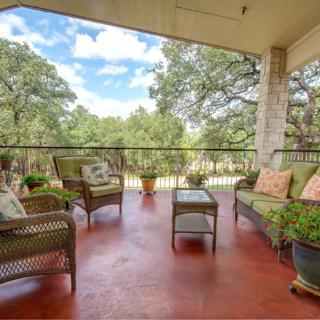 A cozy outdoor patio with wicker furniture and potted plants overlooking a scenic tree-filled landscape.