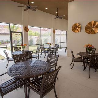 A spacious patio area with tables and chairs, featuring large windows and decorative wall pieces.